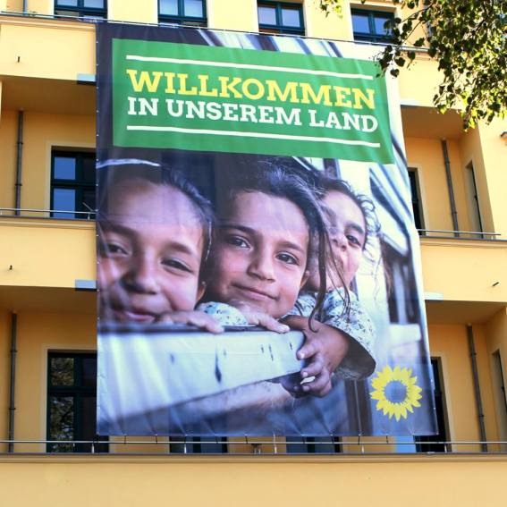 "Bienvenidos a nuestro país." Banner colgante en la fachada de la central de los verdes en Berlin. Fuente: Fan-Page Bündnis90/die Grünen.